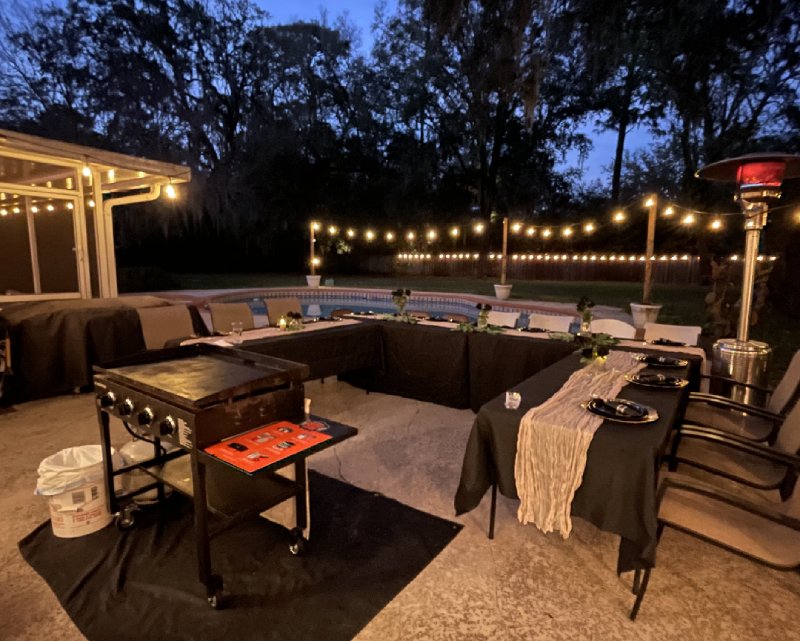 Outdoor hibachi party setup at night with string lights